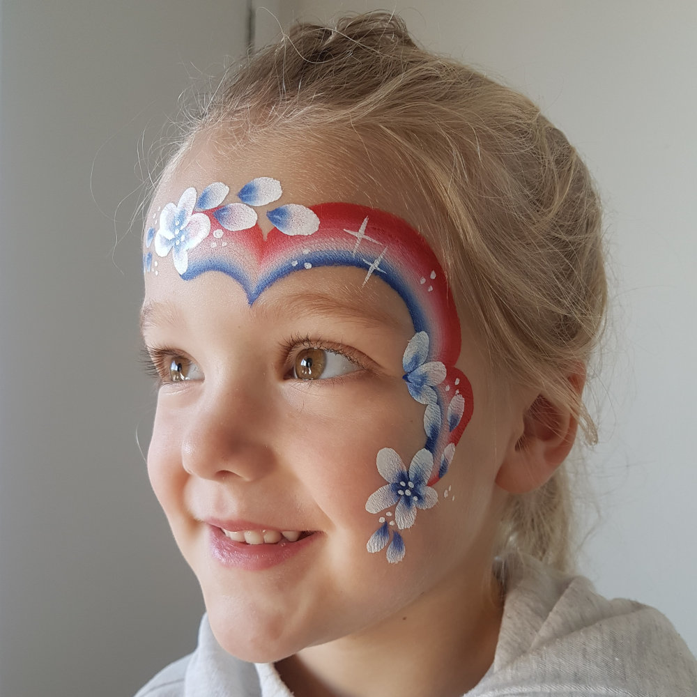 Young girl smiling and wearing red white and blue striped face paint.
